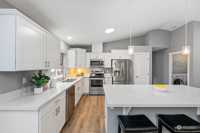 kitchen with pendant lighting, stainless steel appliances, washer / clothes dryer, white cabinetry, and a sink