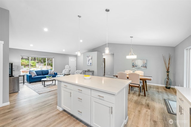 kitchen with decorative light fixtures, light countertops, open floor plan, white cabinets, and vaulted ceiling