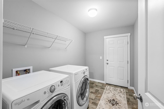 laundry area with baseboards, laundry area, stone finish floor, and washer and dryer