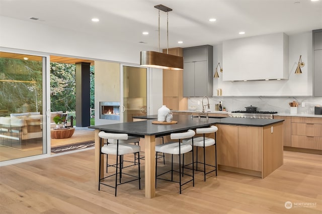 kitchen with an island with sink, light hardwood / wood-style flooring, sink, and a breakfast bar