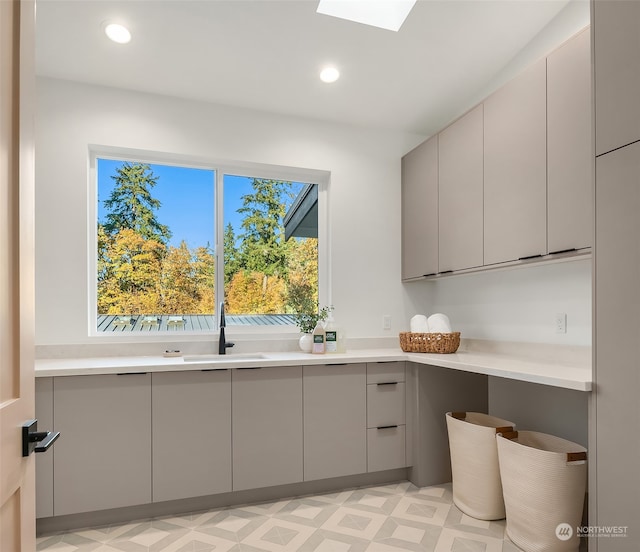 interior space with gray cabinets, a skylight, and sink