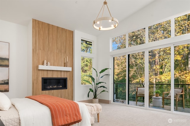 carpeted bedroom with multiple windows, an inviting chandelier, and a large fireplace