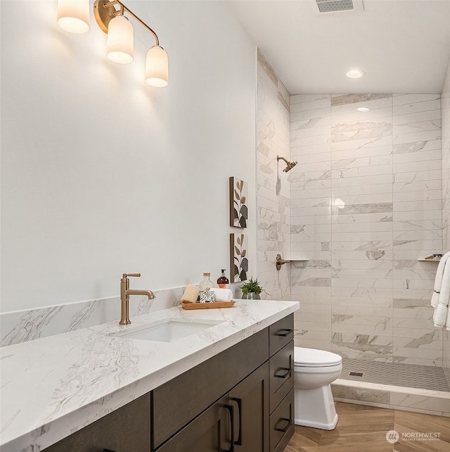 bathroom featuring tiled shower, vanity, hardwood / wood-style flooring, and toilet