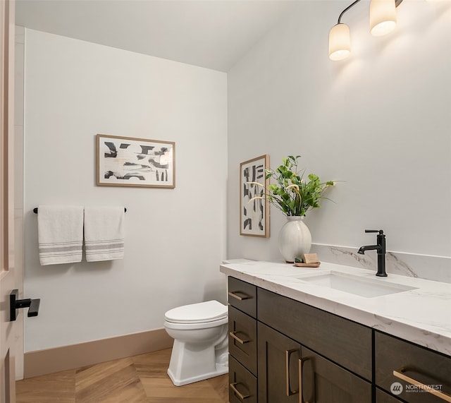 bathroom featuring toilet, vanity, and parquet floors