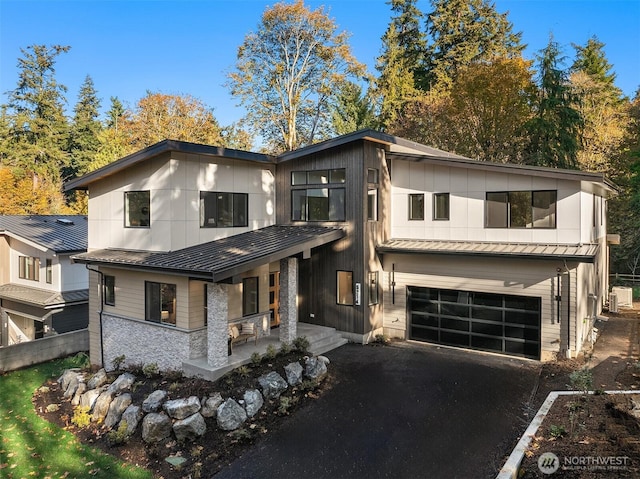 view of front of home with metal roof, a porch, a standing seam roof, and an attached garage