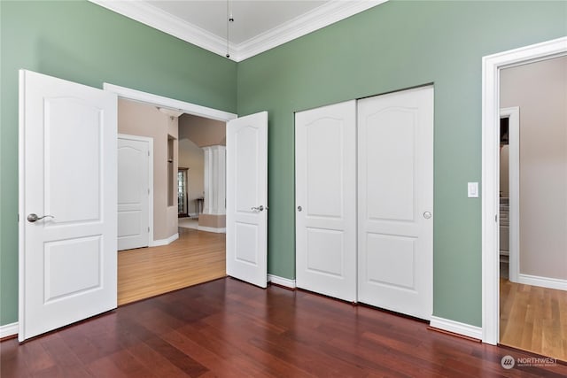 unfurnished bedroom featuring a closet, crown molding, and dark hardwood / wood-style floors