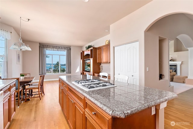 kitchen with a kitchen island, hanging light fixtures, light hardwood / wood-style flooring, and stainless steel gas cooktop