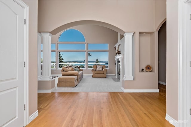 interior space with light wood-type flooring, a high ceiling, and decorative columns