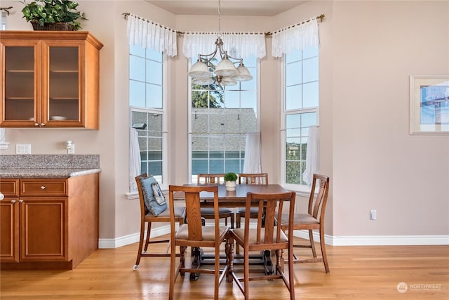 dining area with a notable chandelier, light hardwood / wood-style flooring, and a high ceiling