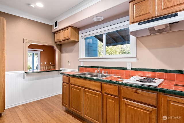 kitchen featuring tile counters, light wood-type flooring, sink, ornamental molding, and white stovetop