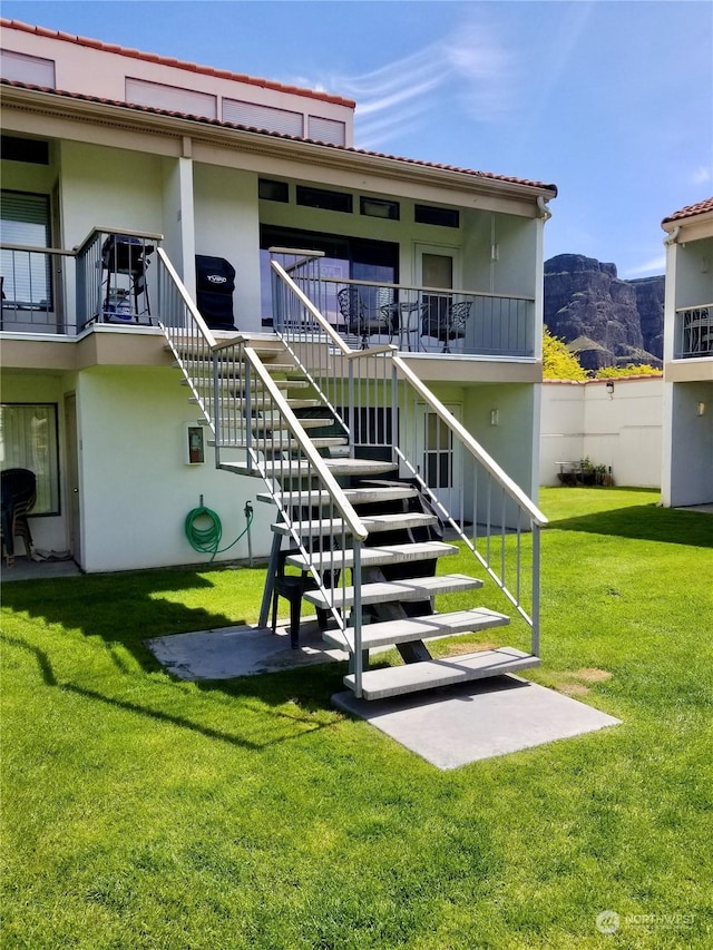 rear view of property featuring a mountain view, a patio area, and a lawn