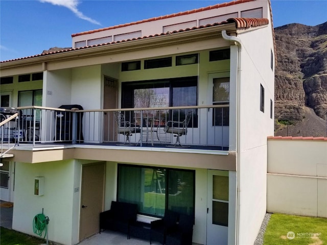 back of house featuring a balcony and a mountain view