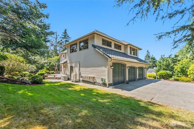 view of front facade featuring a garage, a front lawn, and cooling unit