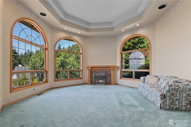 living room with a fireplace, carpet, a tray ceiling, and a healthy amount of sunlight