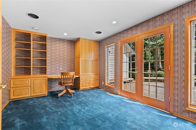 unfurnished office featuring dark carpet, french doors, and built in desk