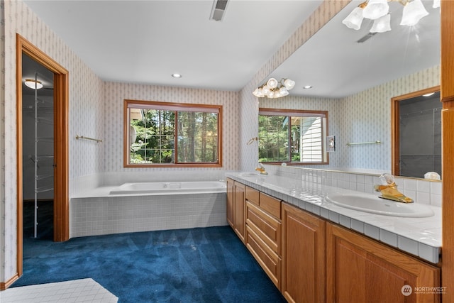 bathroom with tiled tub and double vanity