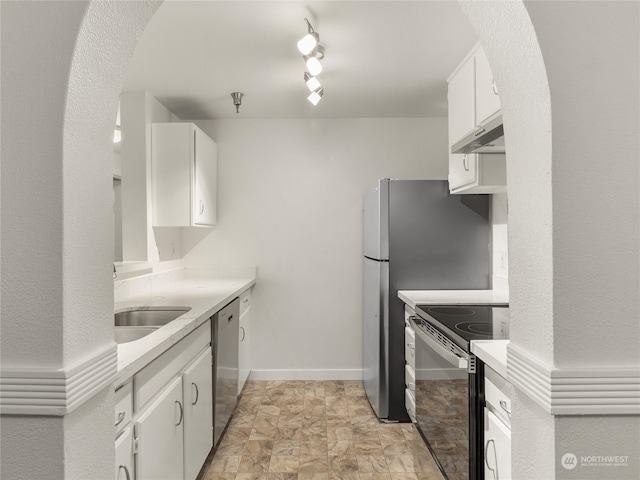 kitchen featuring appliances with stainless steel finishes, sink, rail lighting, light tile patterned flooring, and white cabinetry