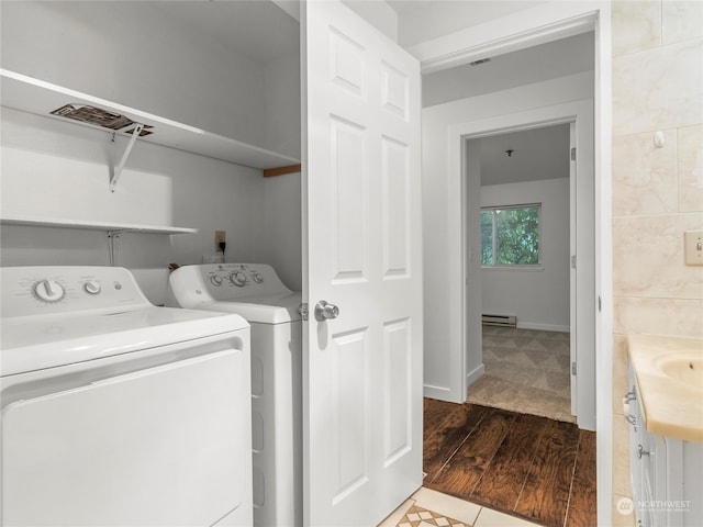 washroom featuring separate washer and dryer, a baseboard radiator, and hardwood / wood-style flooring