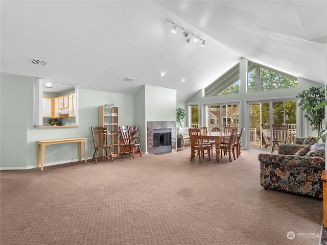 carpeted living room with track lighting and high vaulted ceiling