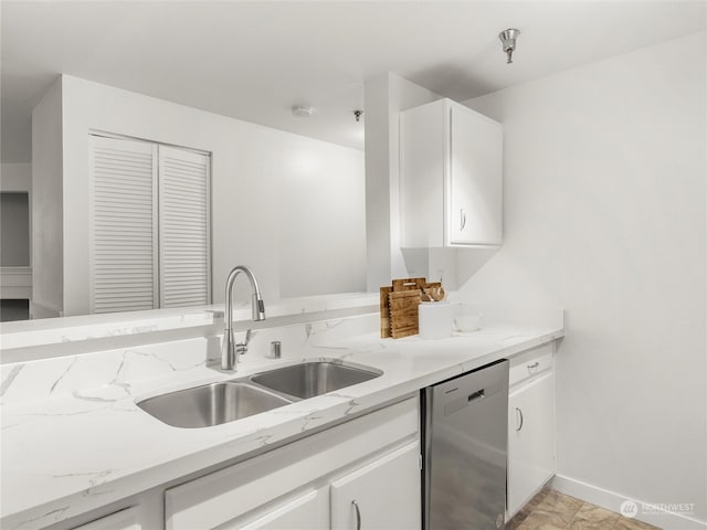 kitchen featuring light tile patterned floors, white cabinets, dishwasher, light stone counters, and sink