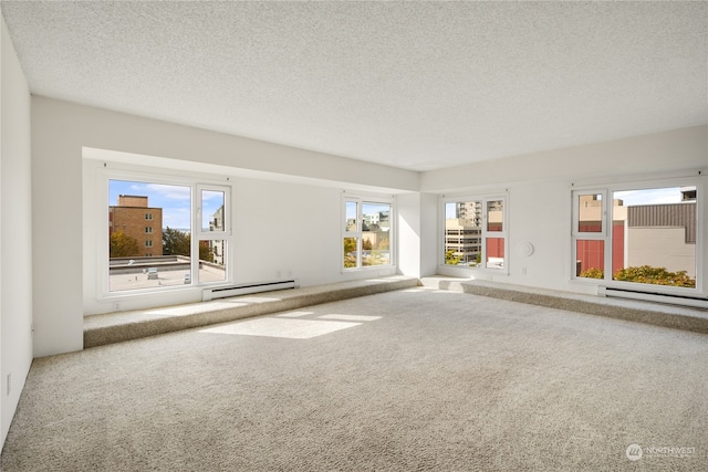 carpeted spare room with a textured ceiling and baseboard heating