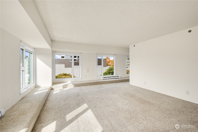 unfurnished living room with carpet floors, a baseboard heating unit, and a textured ceiling