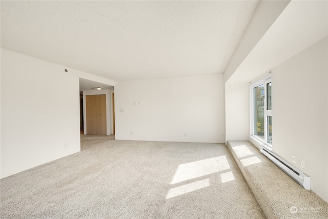 carpeted spare room with a baseboard heating unit