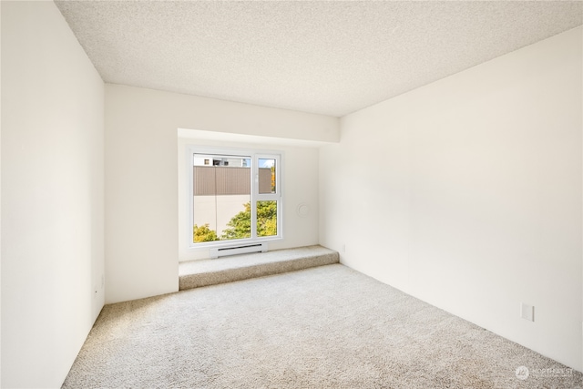 carpeted empty room featuring a baseboard heating unit and a textured ceiling