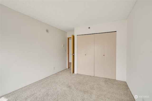 unfurnished bedroom with carpet, a textured ceiling, and a closet