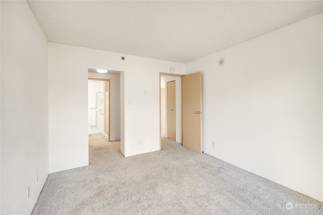 empty room featuring light carpet and a textured ceiling