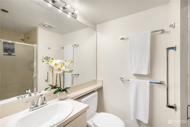 bathroom featuring vanity, a shower with shower door, and toilet