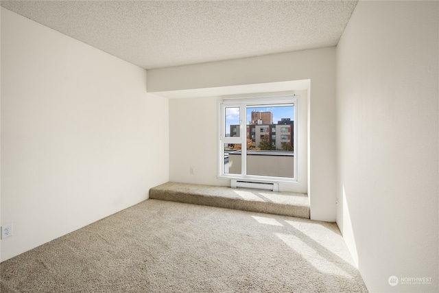 empty room with a baseboard heating unit, carpet, and a textured ceiling