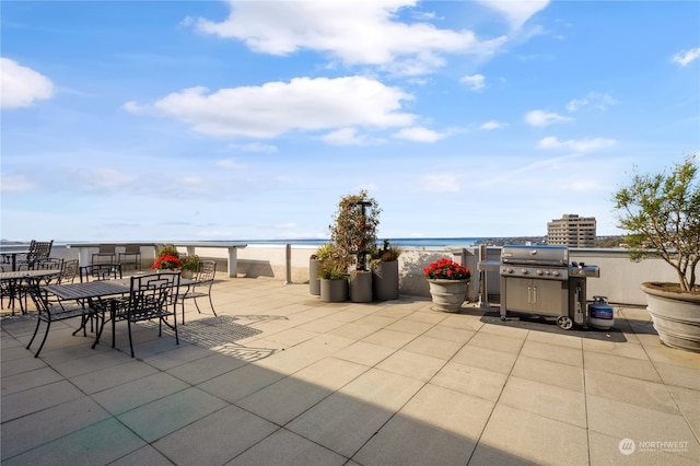 view of patio with a water view, a grill, and a view of the beach