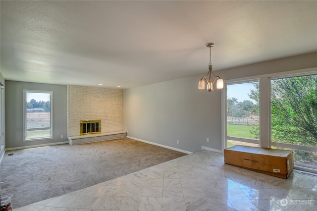 unfurnished living room with brick wall, light carpet, an inviting chandelier, and plenty of natural light