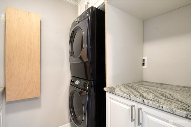 washroom featuring stacked washer and dryer and cabinets