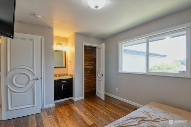 bedroom featuring a closet, connected bathroom, and dark wood-type flooring