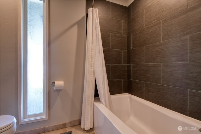 bathroom with tile patterned floors, shower / bathtub combination with curtain, and toilet