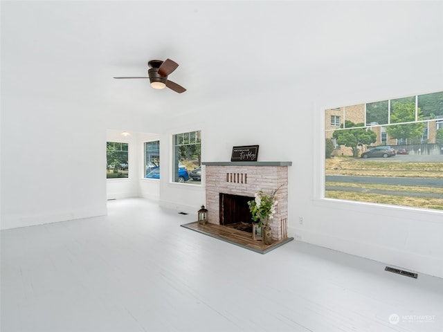 unfurnished living room with ceiling fan and a fireplace