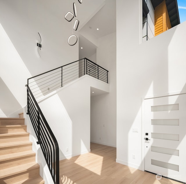 staircase with hardwood / wood-style floors and a towering ceiling