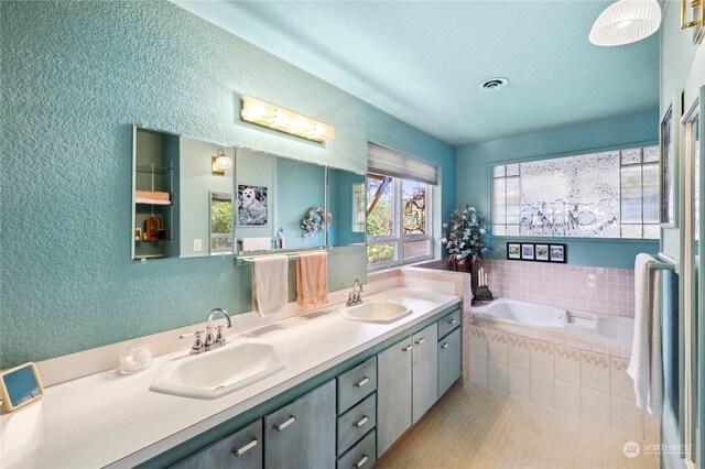 bathroom with vanity and tiled tub