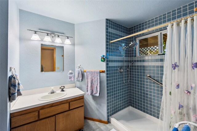 bathroom featuring walk in shower, vanity, a textured ceiling, and tile patterned flooring