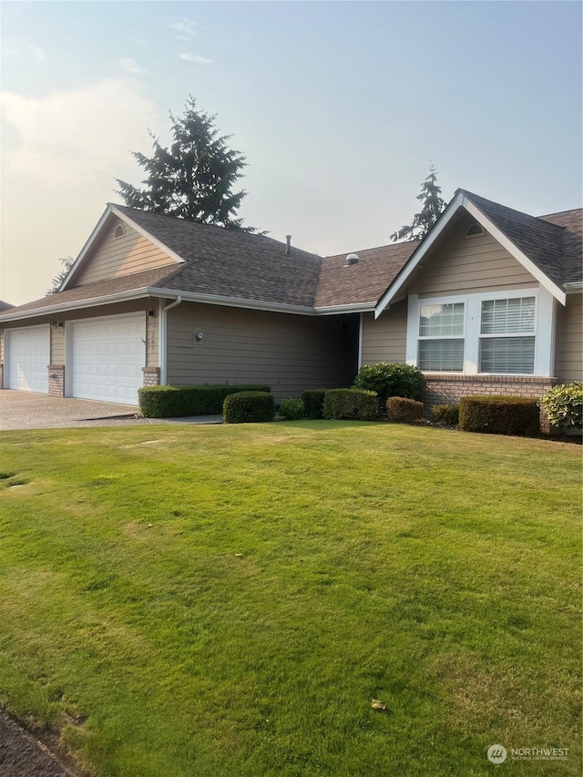 single story home featuring brick siding, a shingled roof, a front lawn, a garage, and driveway