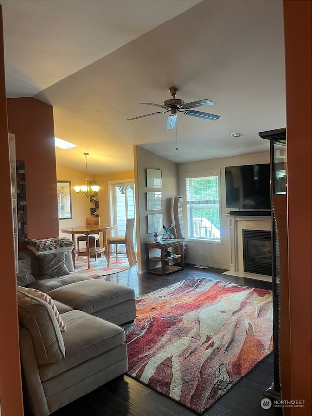 living room with ceiling fan with notable chandelier and hardwood / wood-style flooring