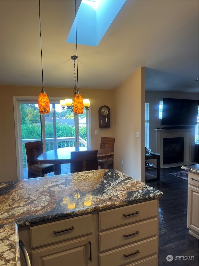 kitchen featuring dark stone countertops, dark hardwood / wood-style flooring, a chandelier, and pendant lighting