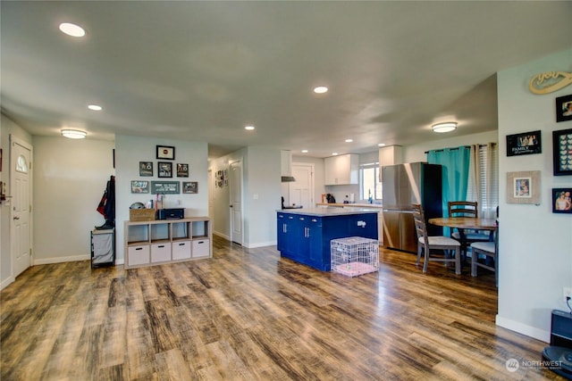 kitchen with stainless steel refrigerator, white cabinetry, hardwood / wood-style floors, and a kitchen island