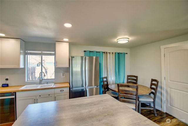 kitchen featuring white cabinetry, stainless steel fridge, black dishwasher, and sink