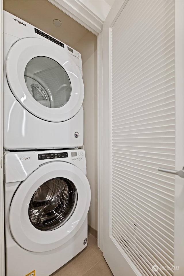 washroom featuring stacked washer and dryer and light tile patterned flooring