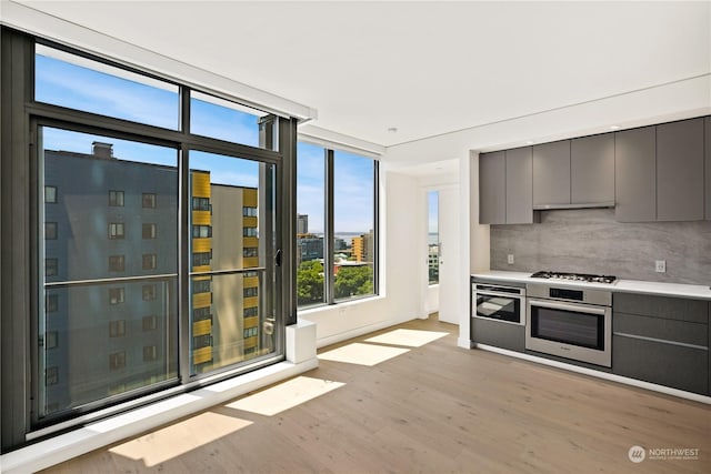 kitchen featuring gray cabinetry, backsplash, stainless steel appliances, and light hardwood / wood-style floors