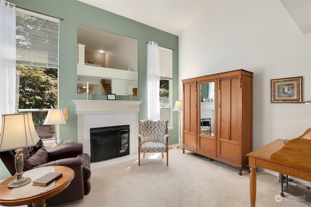 sitting room with light carpet, a tiled fireplace, and plenty of natural light