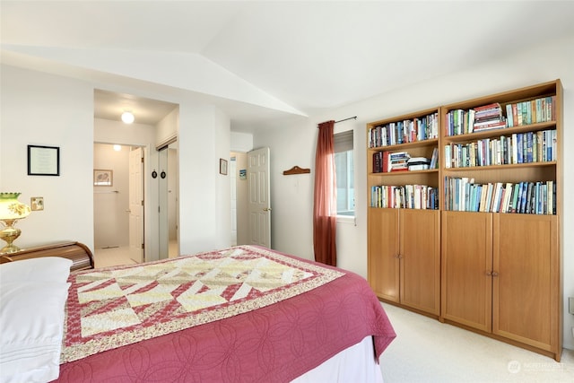 bedroom featuring a closet, light colored carpet, and vaulted ceiling